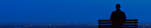 person on a park bench looking at a night city skyline